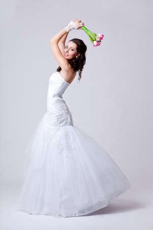 beautiful bride holding bouquet studio full length portrait holding bouquet over headの写真素材