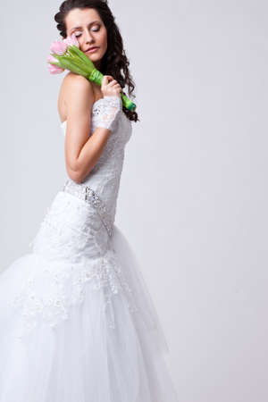 beautiful bride holding bouquet on shoulder studio portrait and closed her eyesの写真素材