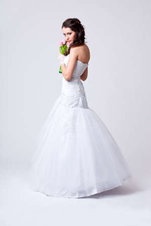 beautiful bride holding bouquet studio full length portrait, she turned her back to the cameraの写真素材