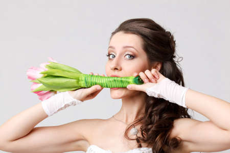 beautiful bride holding bouquet in her mouthの写真素材