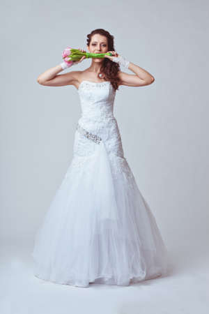 beautiful bride holding bouquet in her mouthの写真素材