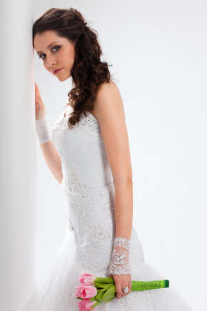 beautiful bride standing near white column and looking to the camera, studio shotの写真素材