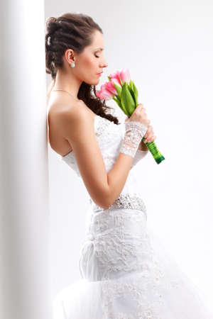 beautiful bride standing back to the  white column with closed eyes, studio shotの写真素材