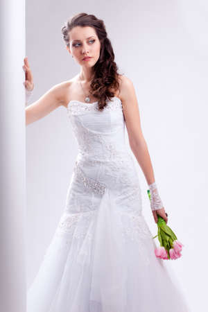beautiful bride standing near white column, studio shotの写真素材