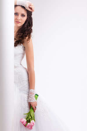beautiful bride standing behind white column, studio shotの写真素材