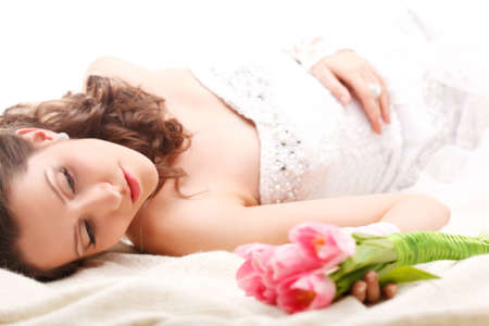 studio photograph of a bride lying on the floor with a bouquet of tulipsの写真素材