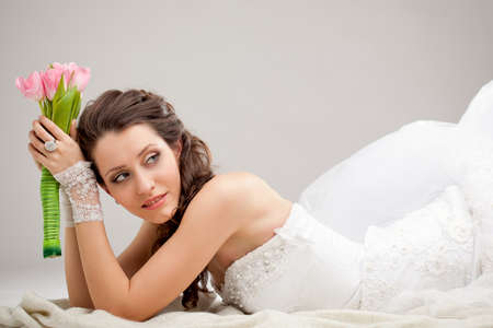 studio photograph of a bride posing on the floor and looking backの写真素材