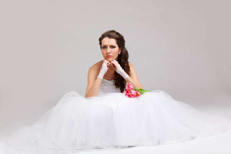 beautiful brunette  bride sitting on the floor and frowingの写真素材