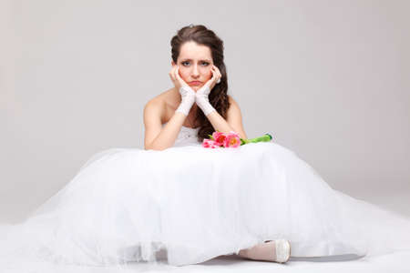 beautiful brunette  bride sitting on the floor and frowingの写真素材