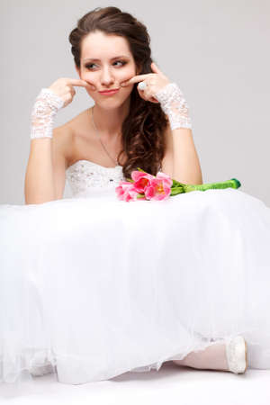 beautiful brunette  bride sitting on the floor and doing smileの写真素材