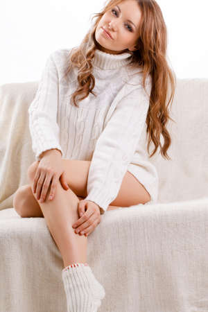 beautiful sexy woman wearing sweater sitting on the sofaの写真素材
