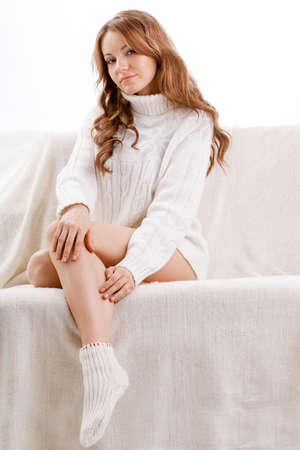 beautiful sexy woman wearing sweater sitting on the sofaの写真素材