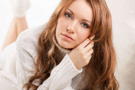 beautiful sexy woman wearing sweater lying on the sofaの写真素材