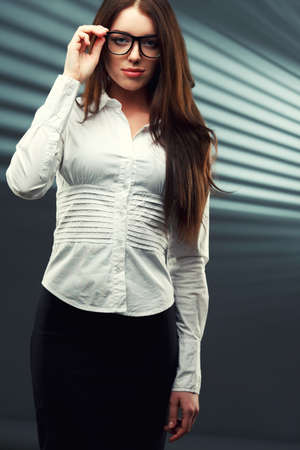businesswoman wearing glasses in front of a striped background looking at the camera and holding glassesの写真素材