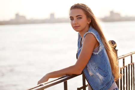woman is leaning on the railing over river on backgroundの写真素材