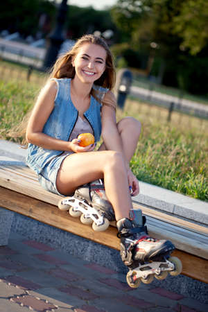 smiling roller girl sitting on the bench and holding appleの写真素材