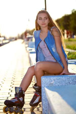 roller girl wearing jeans sitting on bench outdoorsの写真素材