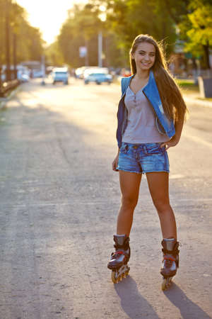 smiling beautiful woman skating outdoors  during sunsetの写真素材
