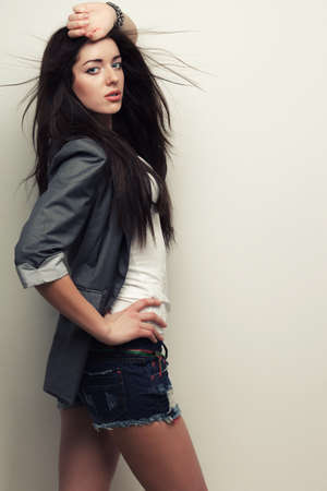 woman fashion studio portrait with flying hair over white wall, holding hand over headの写真素材