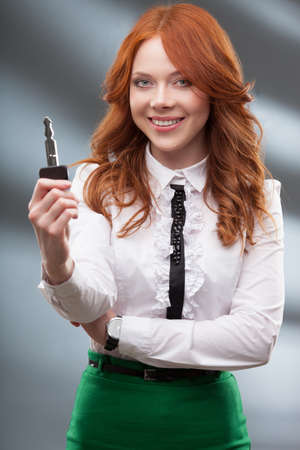 happy red haired woman holding big keyの写真素材