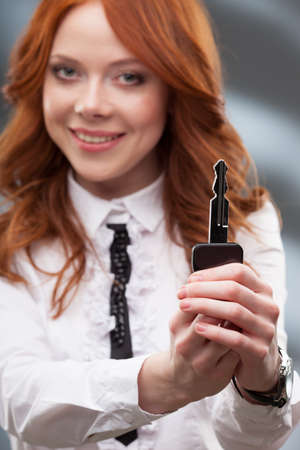 happy red haired woman giving big keyの写真素材
