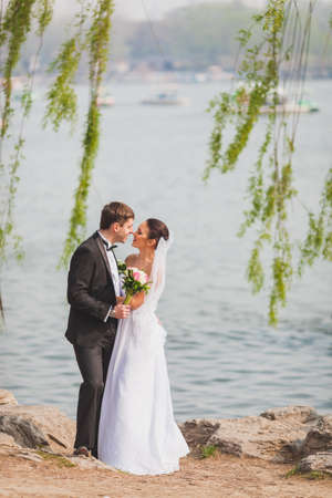 beautiful lovely bridal couple standing near lake, vertical photoの写真素材
