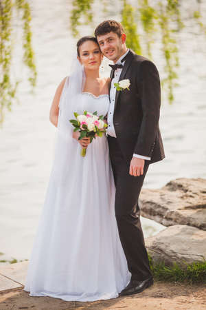 beautiful lovely bridal couple standing near lakeの写真素材