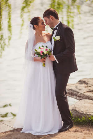 beautiful lovely bridal couple standing near lakeの写真素材