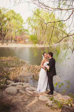bridal couple standing near lake on stonesの写真素材