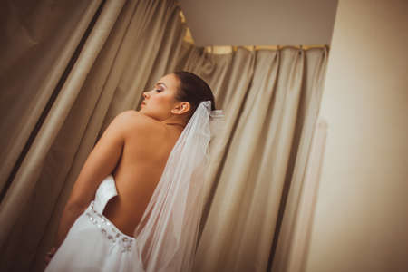 portrait of beautiful brunette bride with closed eyes near windowの写真素材