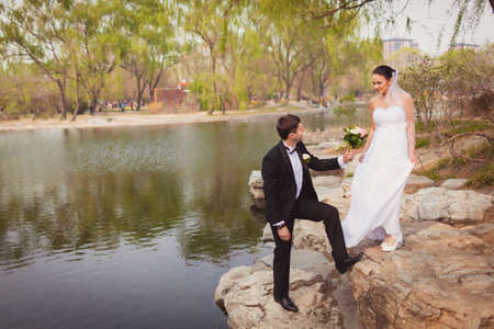 bridal couple standing on stones near lake in the parkの写真素材