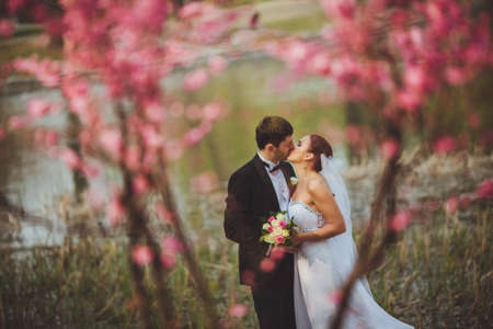 happy bridal couple kissing in parkの写真素材