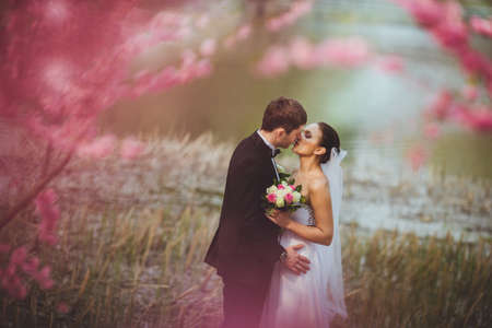 happy bridal couple kissing in parkの写真素材