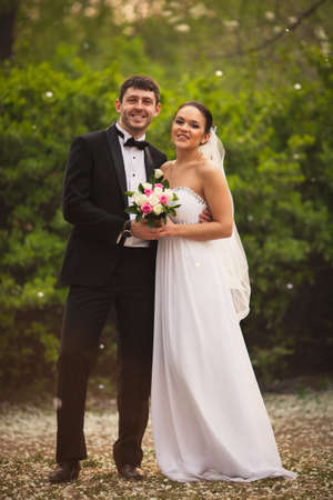 bride and groom in park with falling petals closeup portraitの写真素材