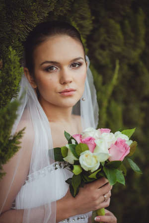 beautiful bride closeup portrait over green trees outdoor, verticalの写真素材