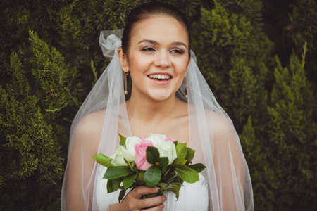 beautiful smiling bride closeup portrait over green trees outdoorの写真素材