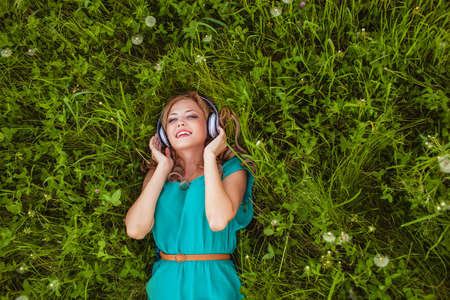woman laying on green grass with headphonesの写真素材