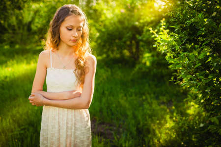 beautiful woman walking in the summer park on sunset looking downの写真素材