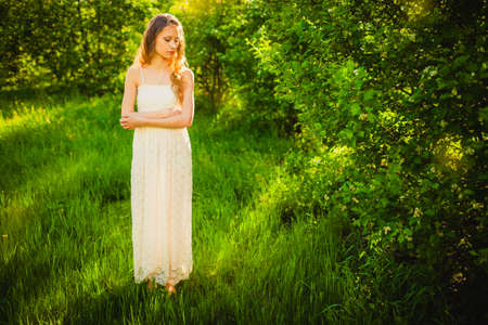 beautiful woman walking in the summer park on sunset looking downの写真素材