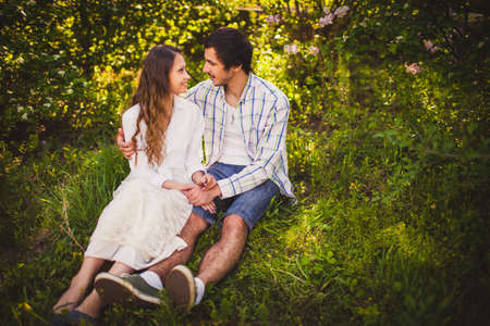 young adult couple in love sitting and hugging at summer parkの写真素材