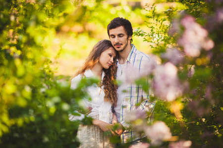 couple in love standing at summer park, man with closed eyes holding her handsの写真素材