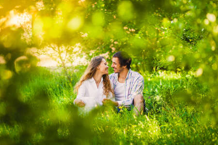 smiling adult couple in love sitting and hugging at summer parkの写真素材