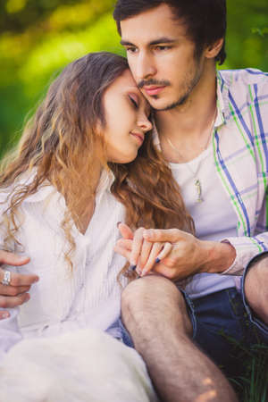 smiling adult couple in love sitting and hugging at summer park, closeup photoの写真素材