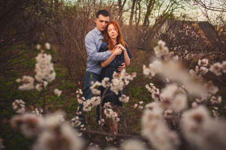 couple hugging in the garden among the blooming trees, flowers in the foregroundの写真素材