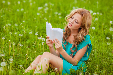 serious woman sitting reading book outdoorsの写真素材