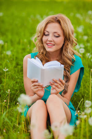 serious woman sitting reading book outdoorsの写真素材