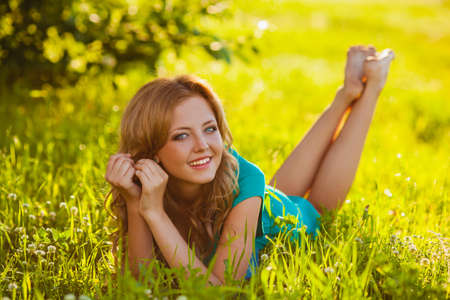 happy blonde woman lying on grass at parkの写真素材