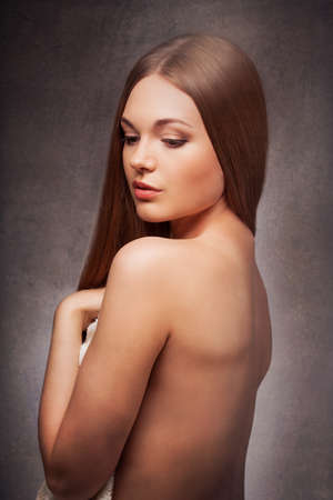 beautiful woman in the fog with naked back portrait over dark background, looking downの写真素材