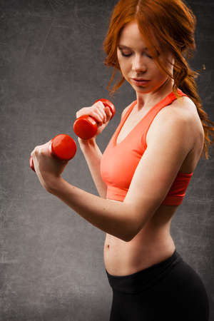 red -haired woman excersising with red dumbbellsの写真素材