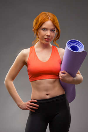 red -haired woman holding fitness matの写真素材